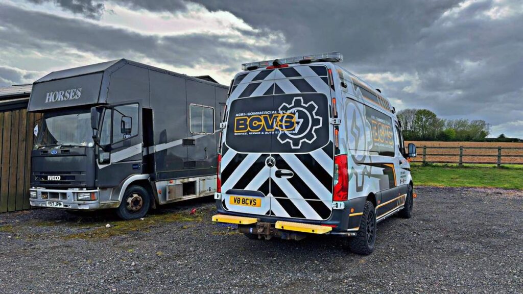 Rear of the chevron-liveried BCVS van beside a horsebox lorry on a gravel yard