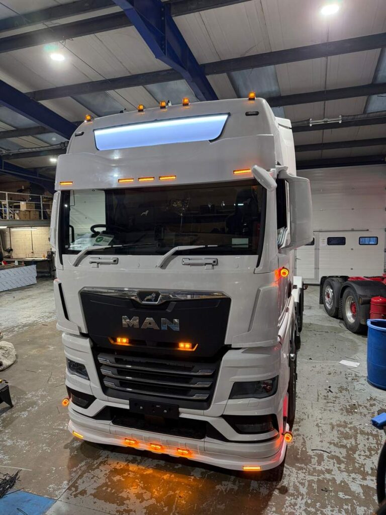 White MAN tractor unit parked in a workshop bay during electrical repairs