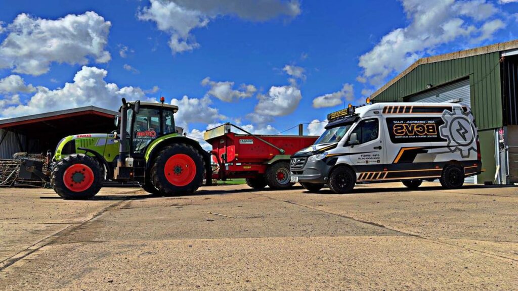 Tractor and spreader beside the BCVS van in a farmyard under a clear blue sky