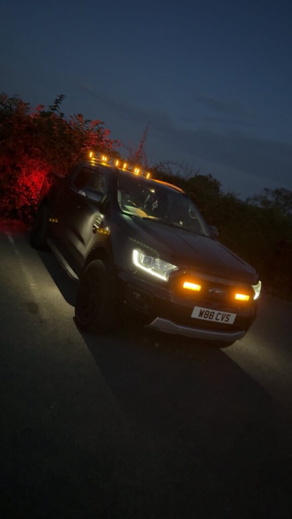 Ford Ranger pickup on a country lane at dusk with newly fitted amber roof marker lights and grille beacons lit