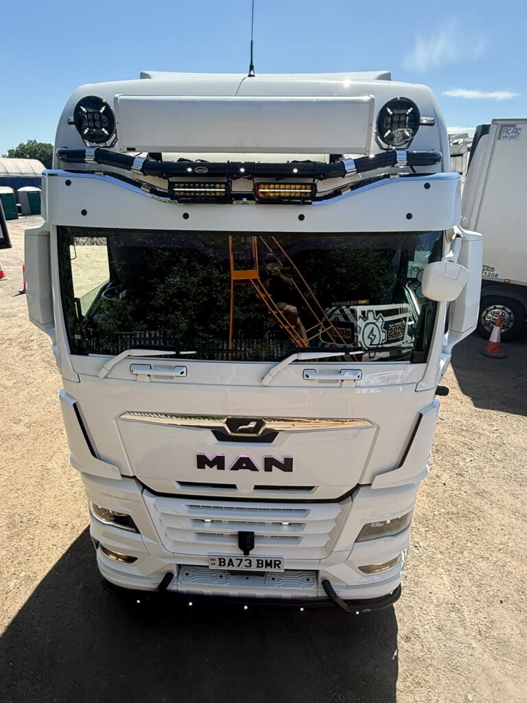 Front of a white MAN tractor unit fitted with a roof light bar, LED work lamps and round spot lamps