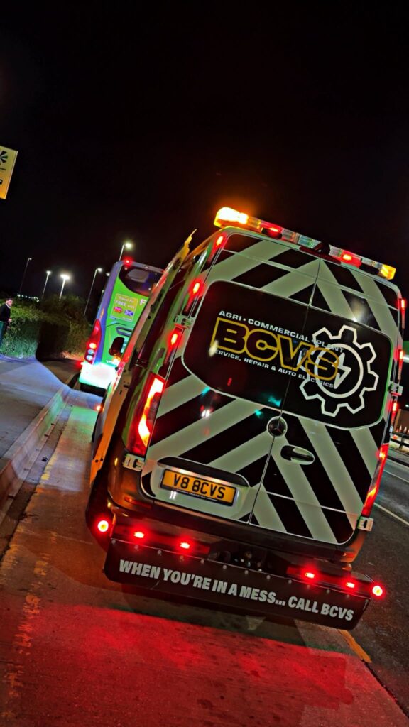 BCVS van under amber beacons at night behind a coach at the roadside