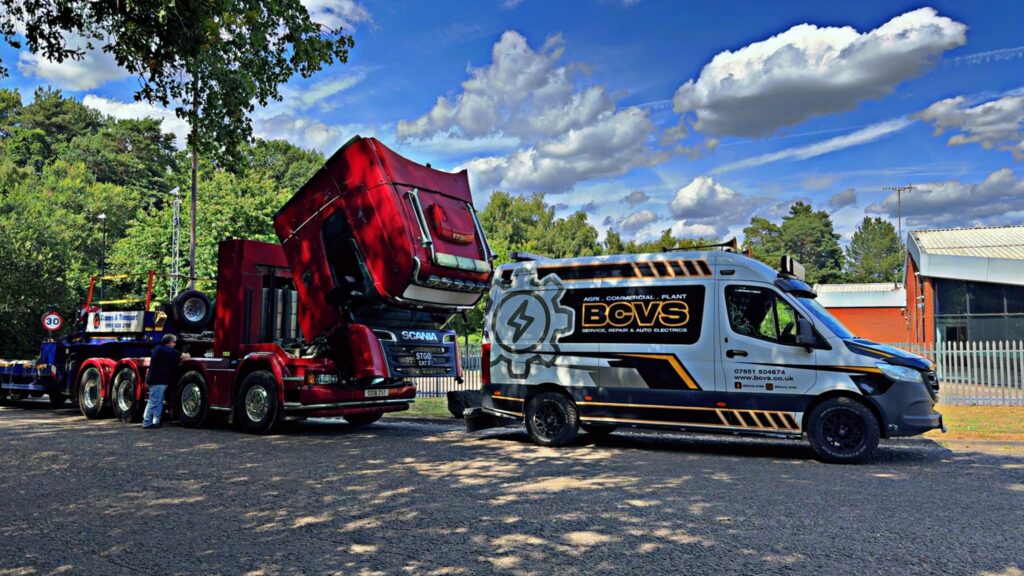 BCVS van next to a red Scania R730 with the cab tilted forward, a technician working on the engine